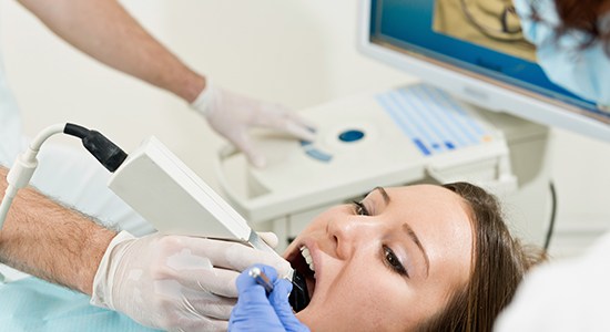 Dentist using hand tool to capture digital impressions of patient's smile