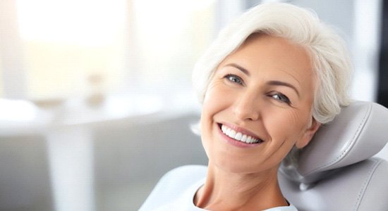 a denture candidate smiling while sitting in the dentist's chair