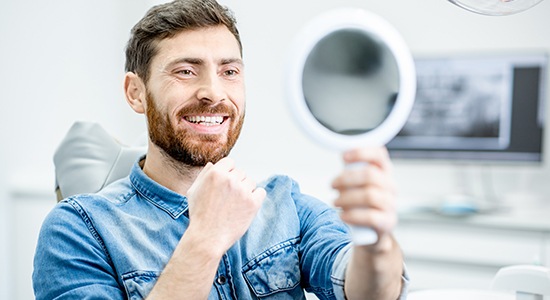 Man looking at smile after professional teeth cleaning