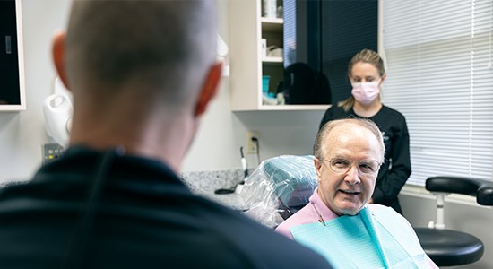 Woman looking at her smile after dental implant tooth replacement