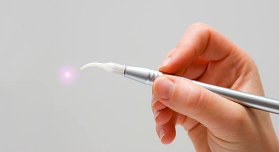 Hand holding a soft tissue laser dentistry hand tool