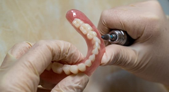 Lab technician filing dentures
