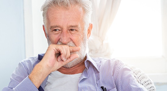 Man covering mouth to hide tooth loss