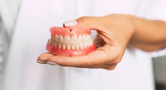 Hands holding a full set of dentures