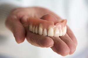 Hand holding a full upper denture