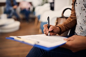 Patient filling out dental insurance paperwork in the waiting room