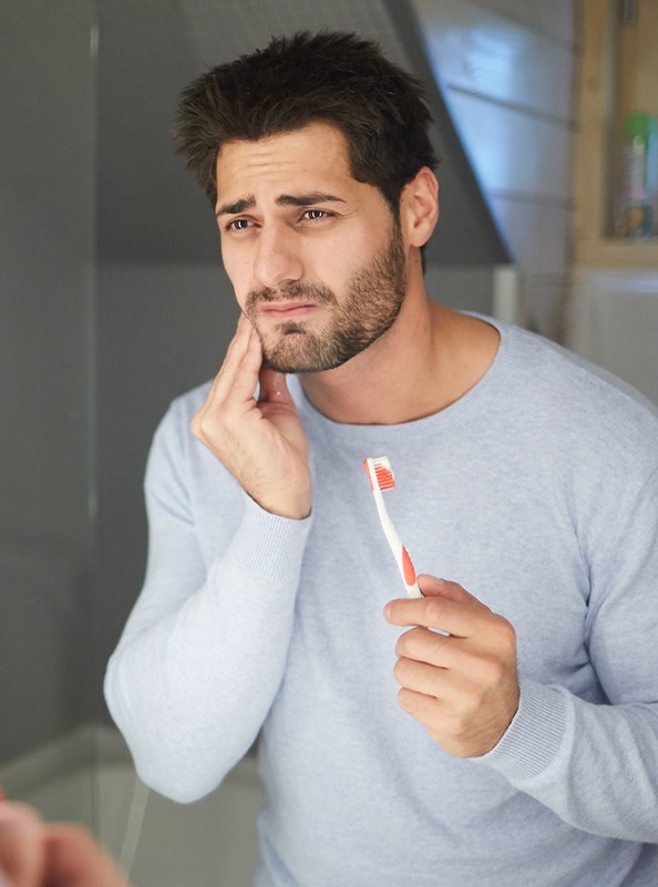 Man in need of emergency dentistry holding jaw