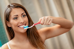 Woman brushing teeth to prevent dental emergencies