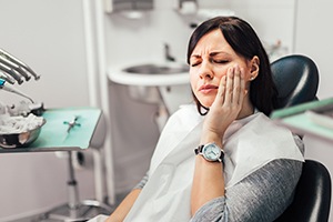 Woman in dental office for emergency dentistry holding cheek