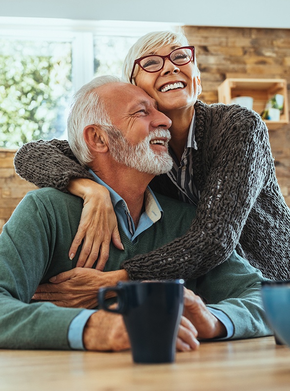 Older man and woman with dental implant supported dentures smiling