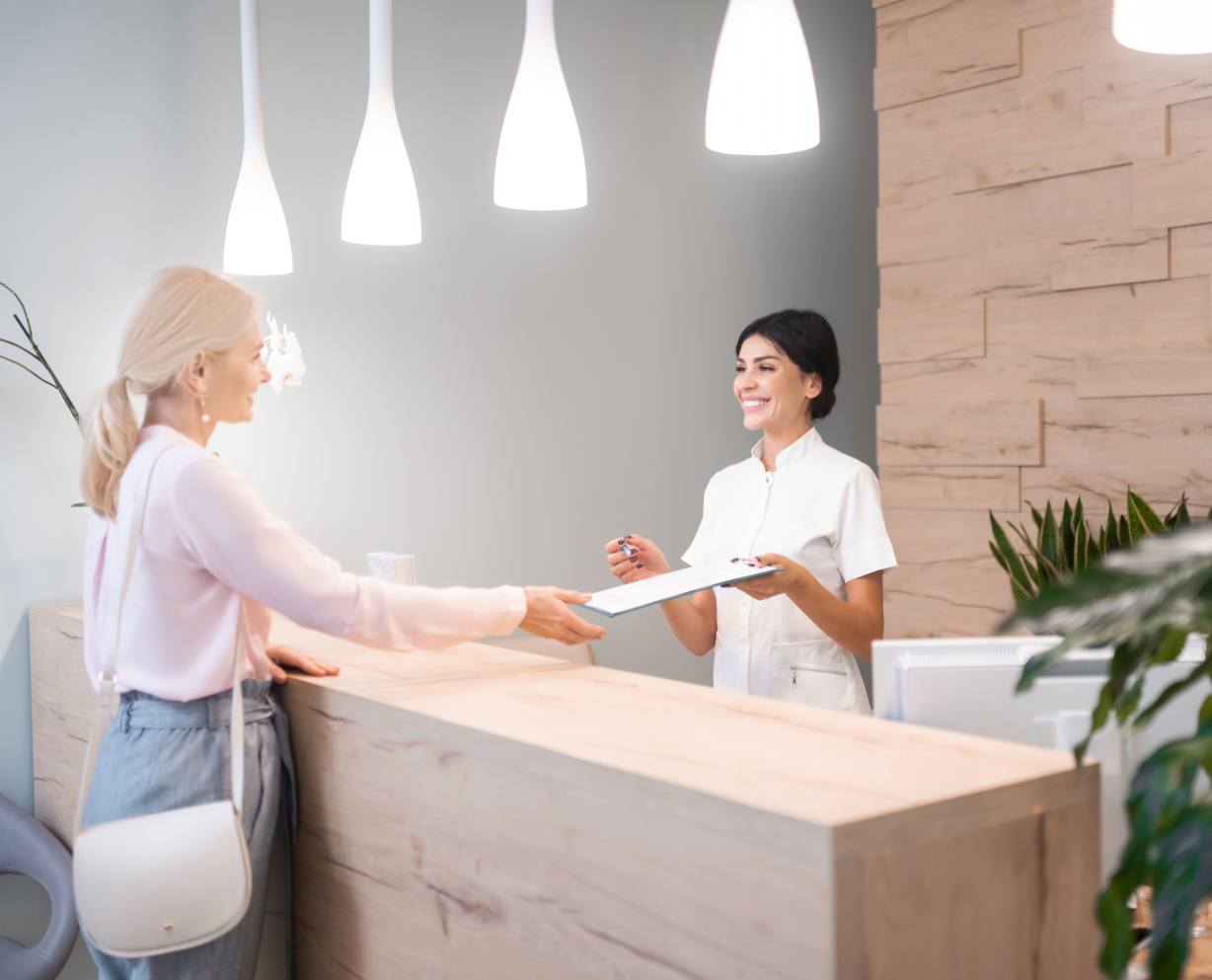 Dental team member greeting patient at reception desk