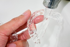 a patient rinsing off their Invisalign aligner