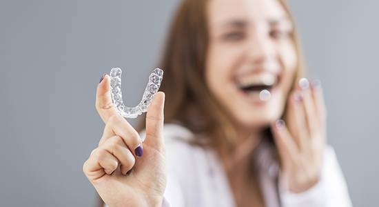 Laughing woman holding her Invisalign tray