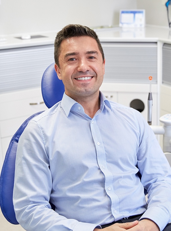 Smiling man in dental office for preventive dentistry treatment