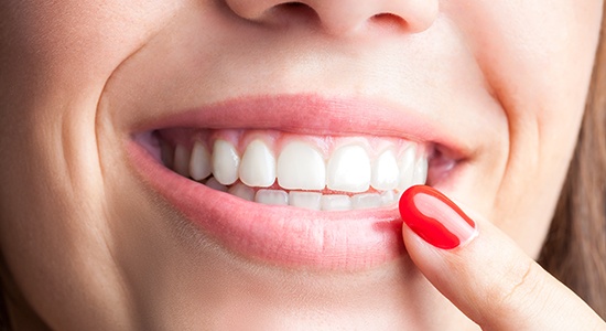 Woman pointing to healthy smile after gum disease treatment