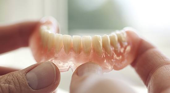 Hand holding full denture