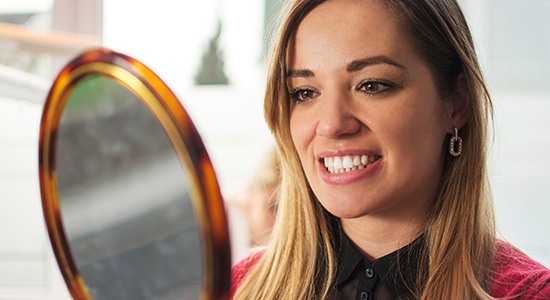 Woman looking at smile after porcelain veneers