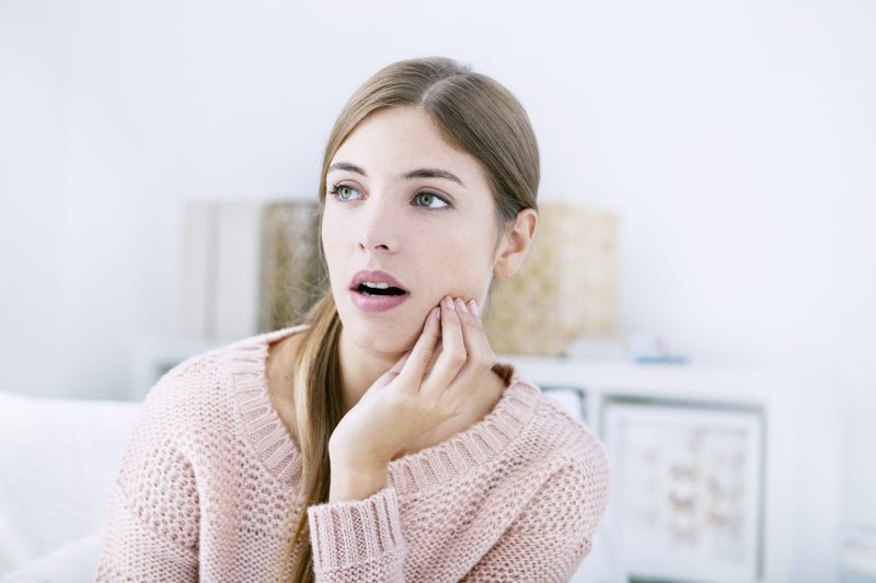 Woman in sweater with jaw pain due to TMD