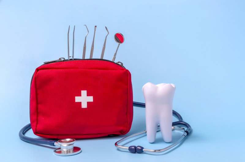 A dental emergency kit next to a large model tooth