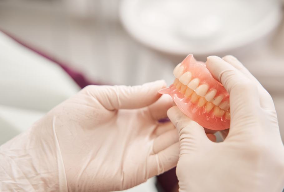 Gloved hands holding dentures